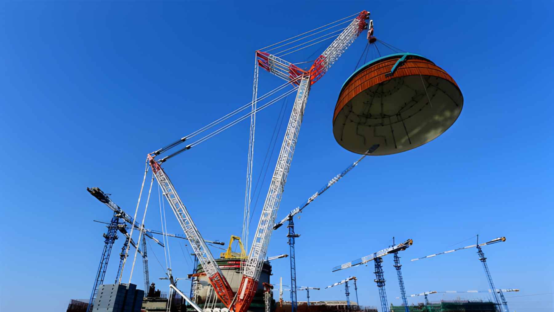 A massive 288-ton steel containment dome being hoisted by cranes at the Lufeng nuclear power plant in China.