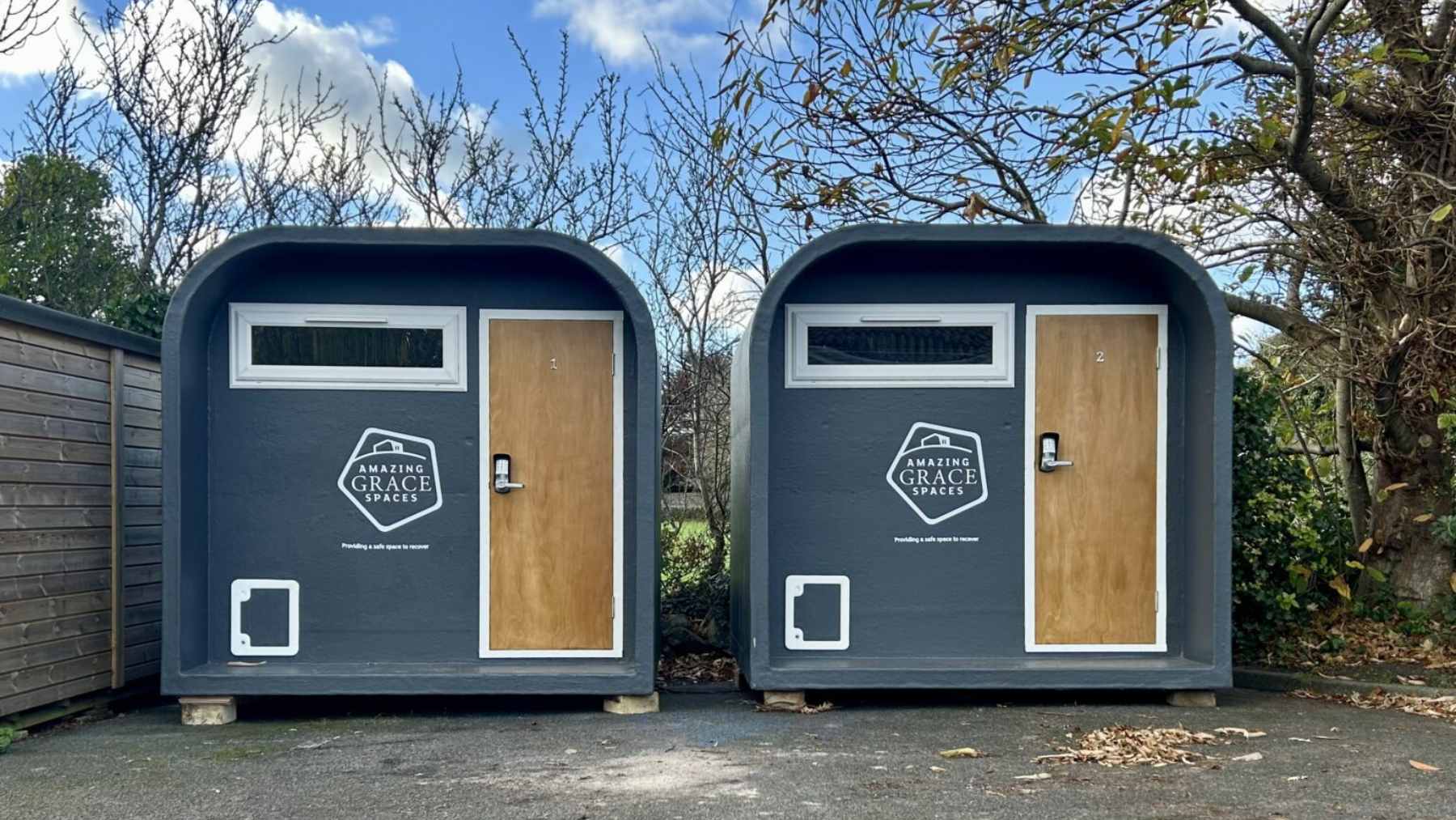 A compact, white solar-powered emergency sleeping pod situated in a Guernsey car park to provide short-term shelter for the homeless.