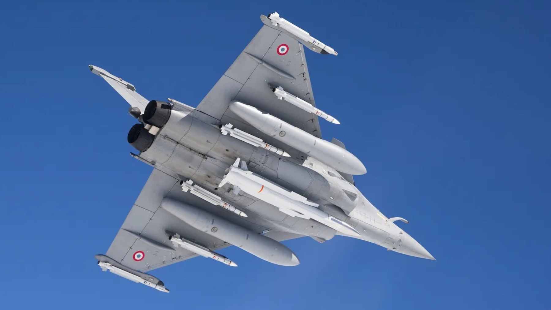 President Emmanuel Macron delivering a speech at the Île Longue nuclear submarine base, flanked by naval personnel and strategic military assets.