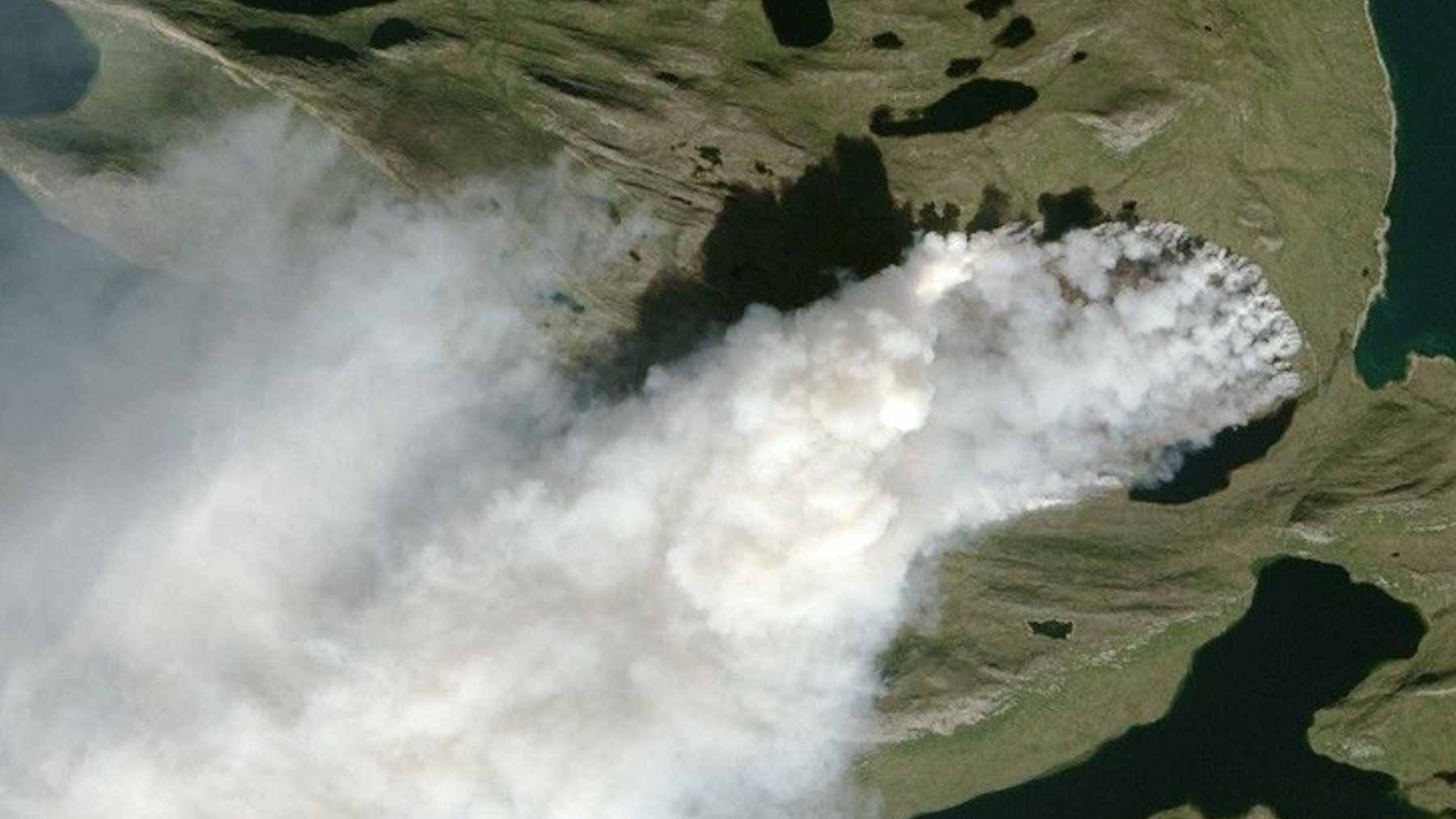 NASA observes the North Pole and encounters a fire and ice phenomenon that seems impossible (but there is an explanation) 1 Satellite view of dark wildfire smoke plumes drifting over white snow-covered tundra and frozen lakes in the Arctic.