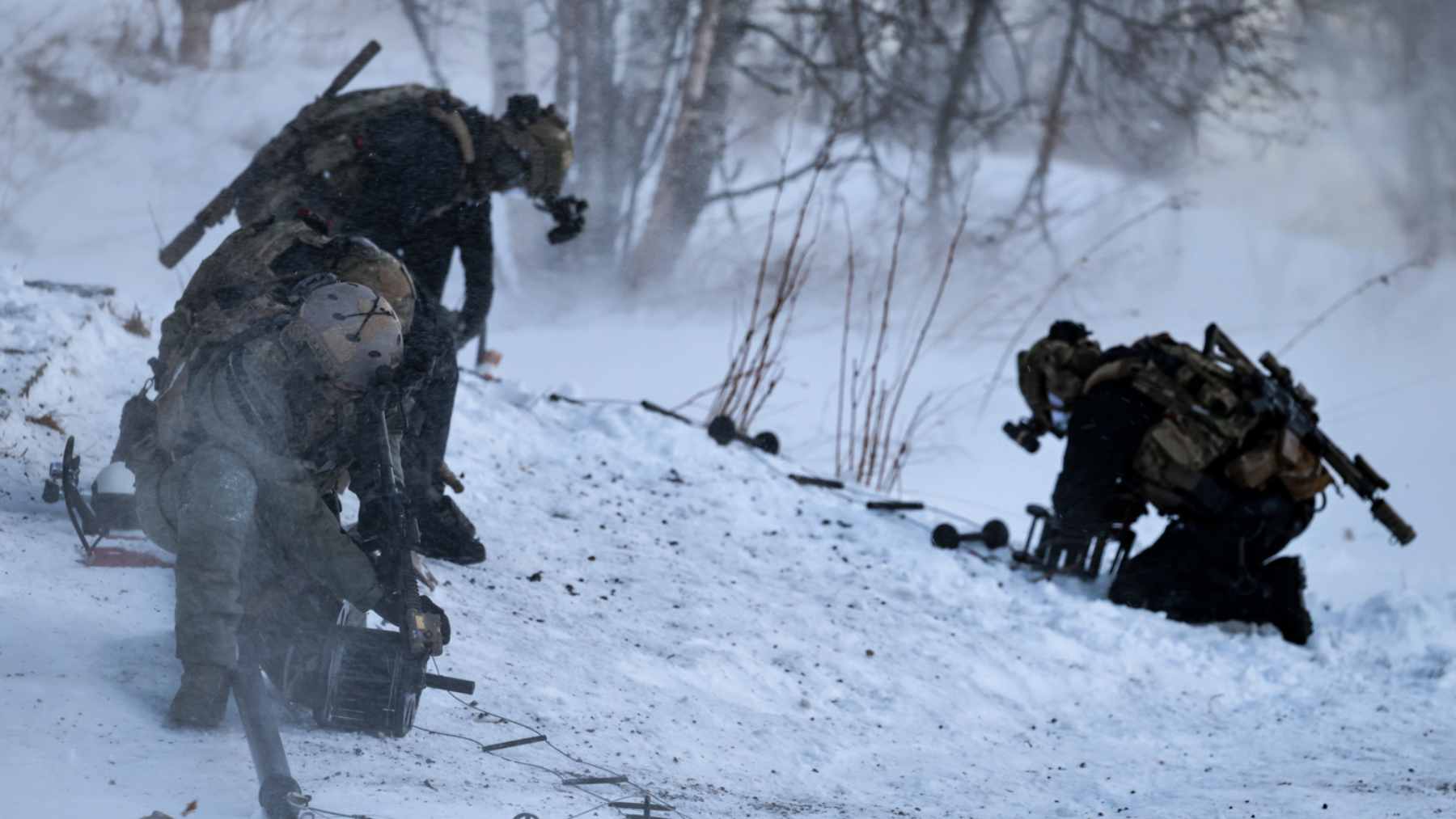 Norwegian elite reconnaissance soldiers digging a quinzhee snow cave for thermal concealment during a military exercise.