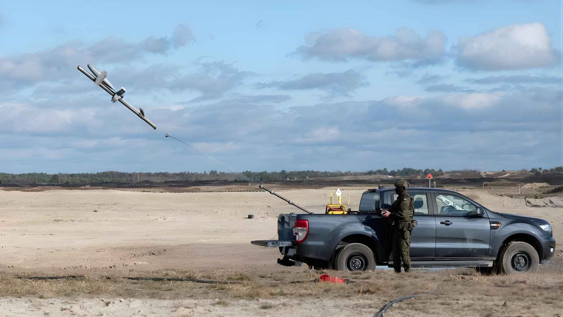 Military personnel operating a portable drone launcher in an open field, illustrating the broader air-defense shift as resources move from Europe toward the Middle East