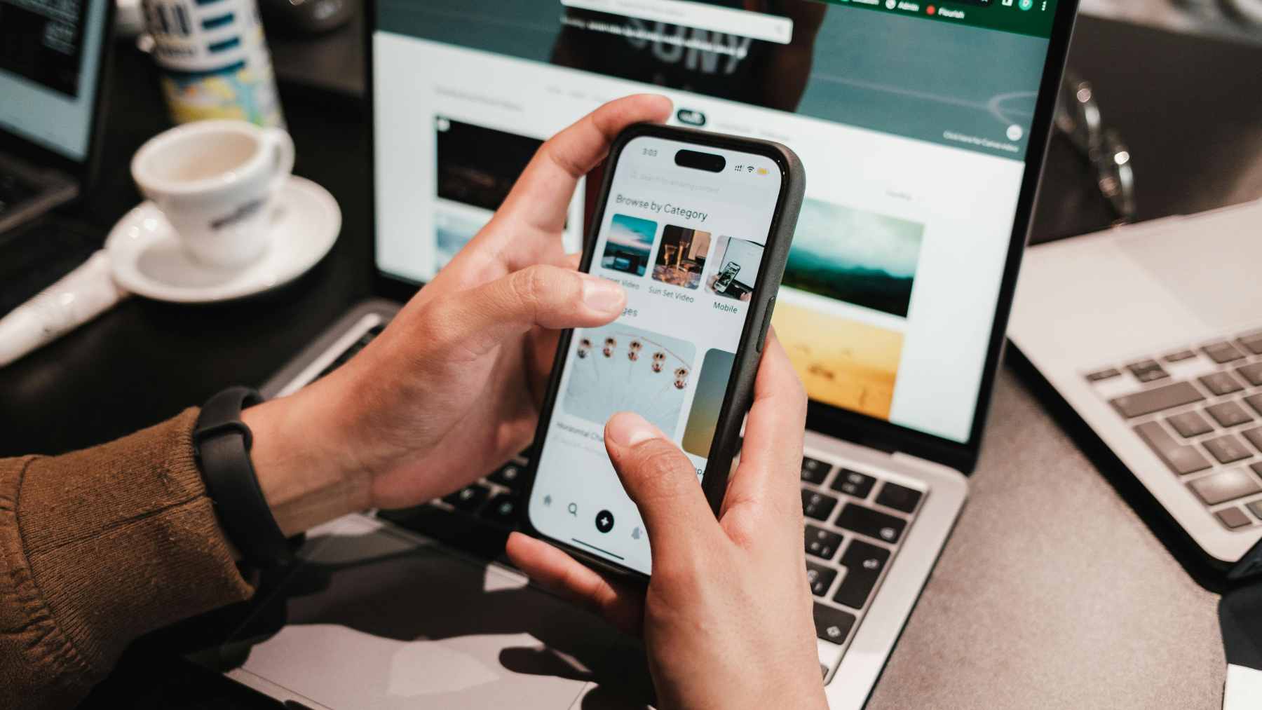 A person’s hand reaching for a buzzing smartphone on a wooden table, illustrating the "bursty" notification-checking behavior studied by Aalto University.