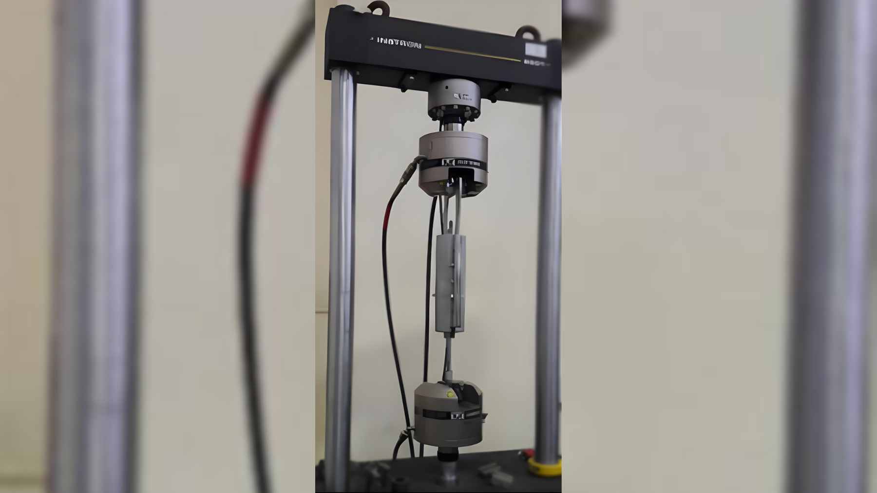 A cross-section view of a passive vibration damper showing a hollow cylinder filled with solid steel balls and a central shaft.