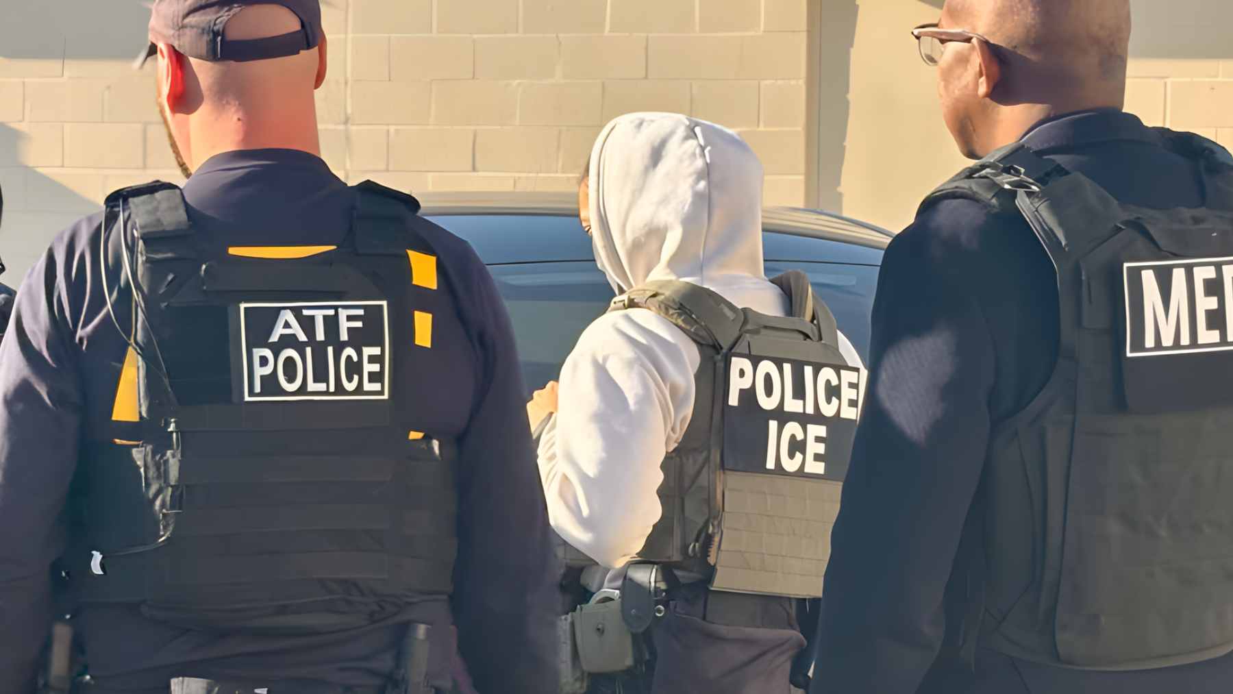 A group of masked federal agents in tactical gear and unmarked black vehicles during an immigration enforcement operation in West Virginia.
