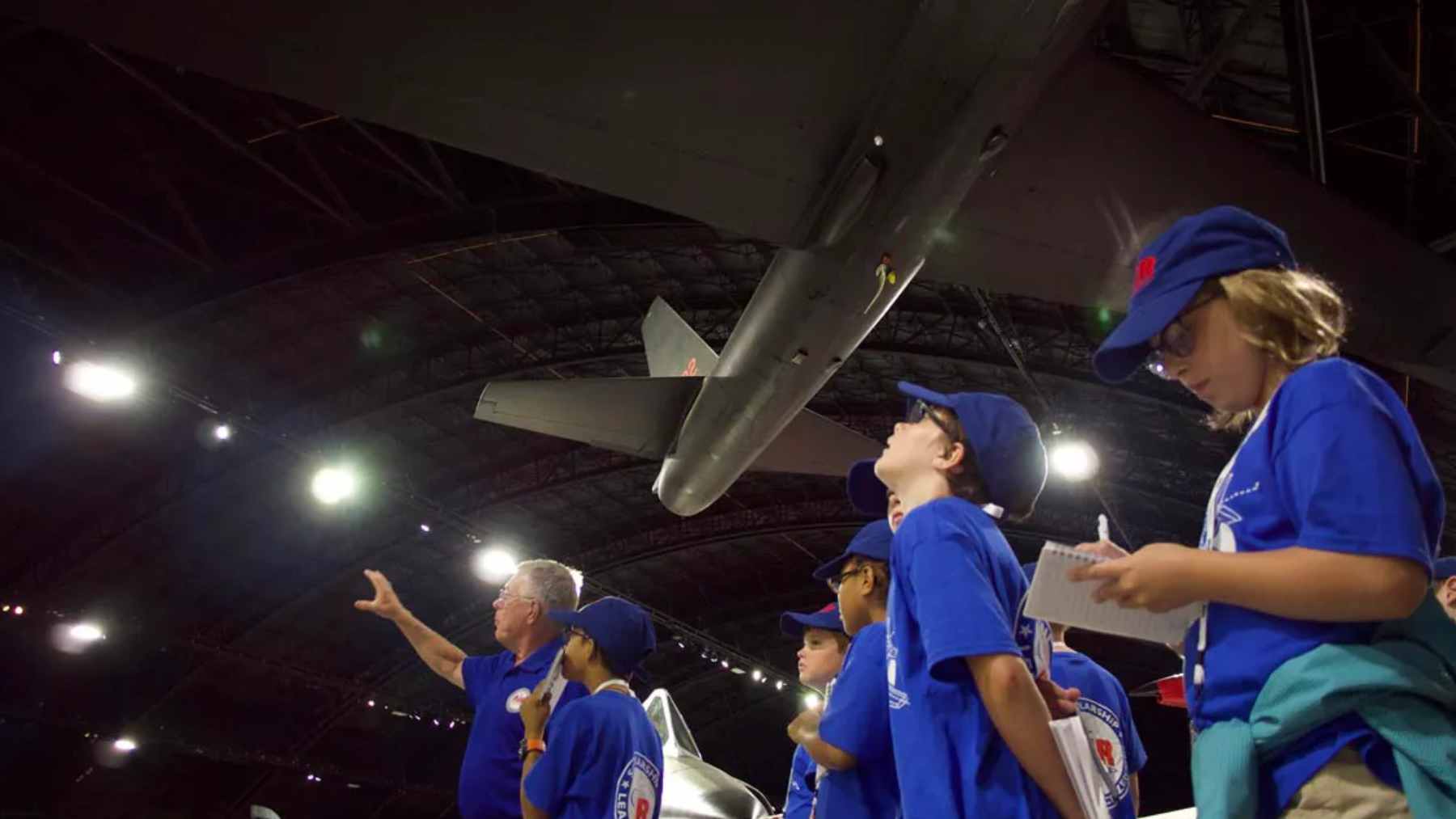 Front aerial perspective of the planned STEM Talent Development Complex at Wright-Patterson Air Force Base, featuring modern architecture and nearby aircraft hangars.