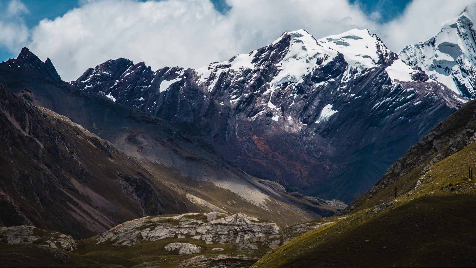 An expansive, dusty open-pit copper mining operation nestled high within the snow-capped peaks of the Andes mountains.