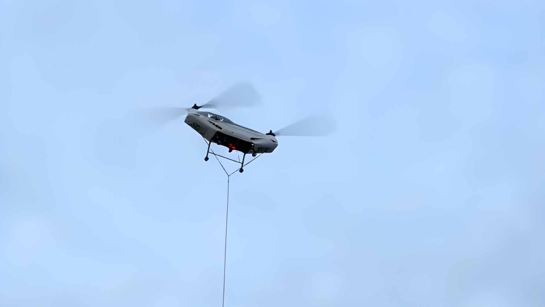 A heavy-lift Chinese unmanned cargo helicopter carrying a large payload over rugged mountainous terrain.