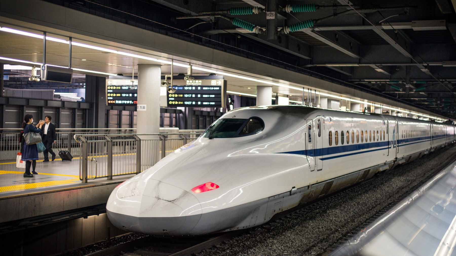 A sleek, high-speed Chinese bullet train entering a massive illuminated concrete tunnel.
