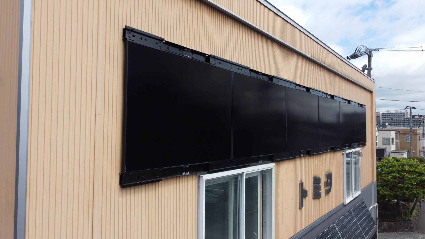 A modern city skyscraper featuring sleek solar panels integrated directly into its vertical exterior facade.