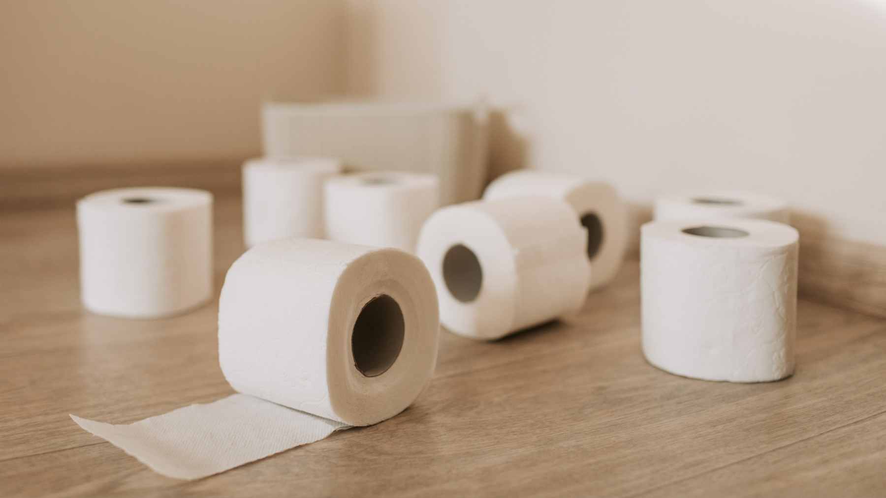 A modern toilet equipped with an electronic bidet wash seat attachment next to a single roll of toilet paper.