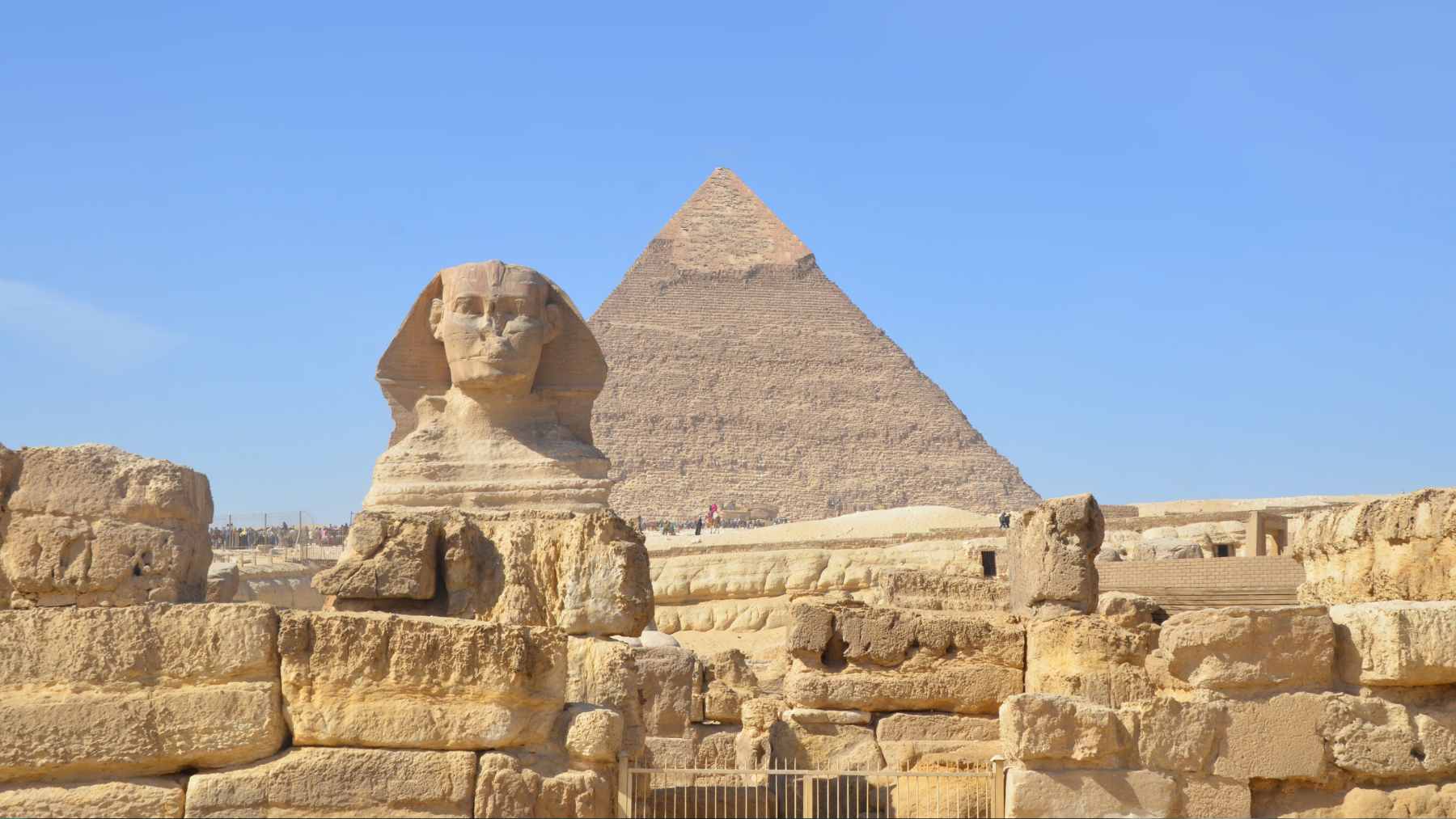 An aerial view of the Giza Plateau showing the Great Sphinx, the pyramids, and surrounding sandy terrain.