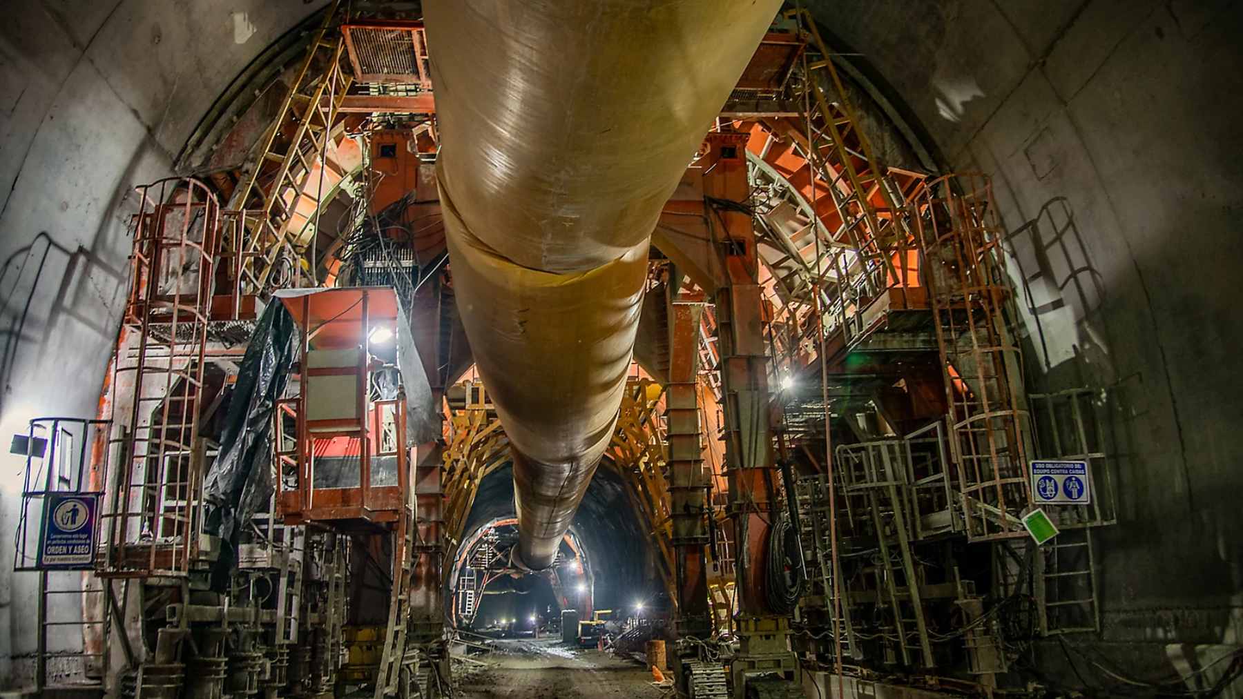 The interior construction of the massive Toyo Tunnel in Antioquia, Colombia, showing reinforced concrete walls and heavy machinery.