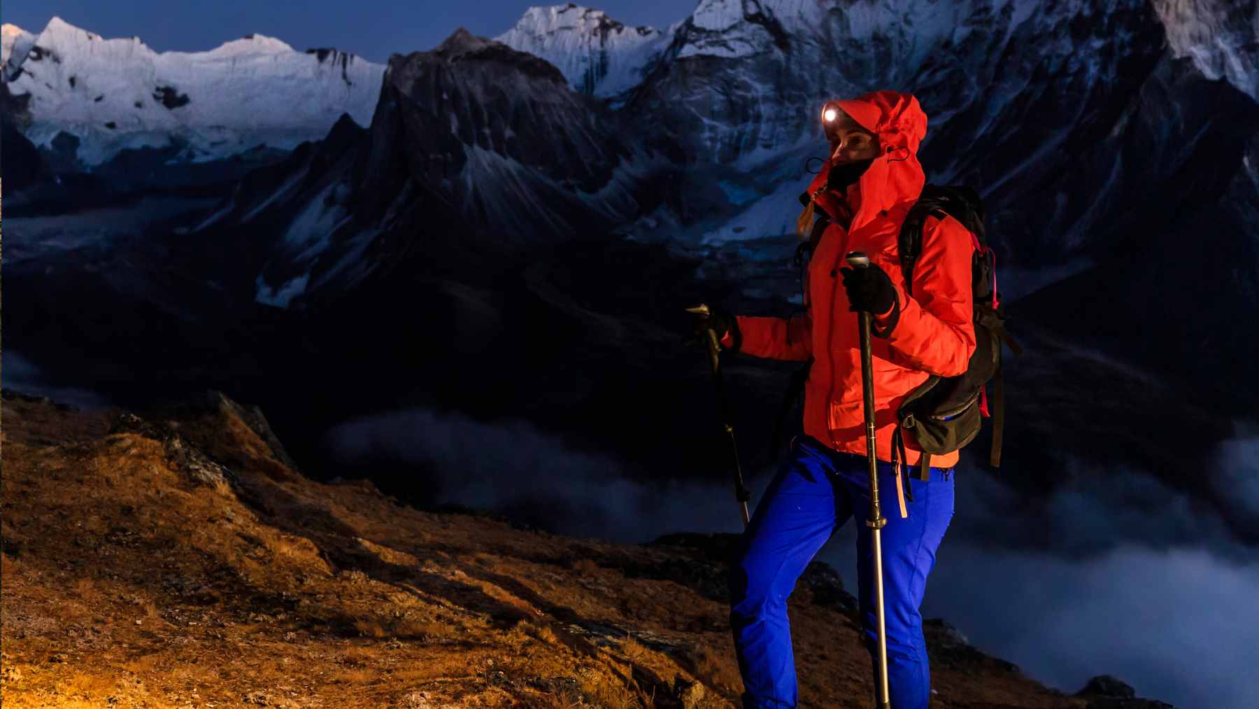 An unprepared day hiker checking a smartphone with zero signal on a rocky, high-altitude mountain trail.