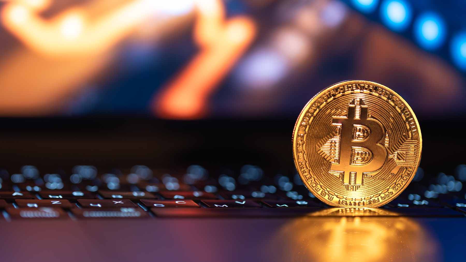 A hooded hacker silhouette overlaid on glowing green computer code and a cryptocurrency logo.