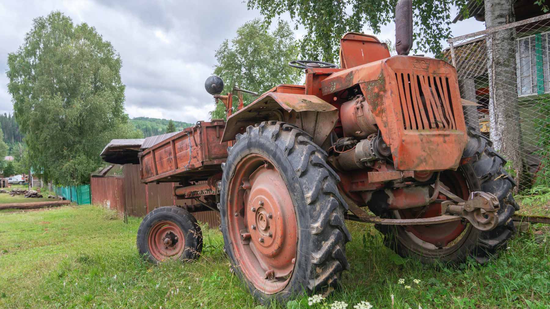 A restored 1957 Ford 640 utility tractor in a field, showing a specific patch of bare steel on the fender where a hand has worn away the paint over decades.
