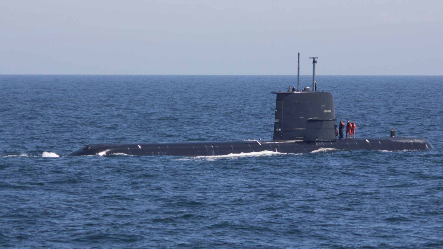 A Royal Navy warship navigating choppy waters while closely shadowing a surfaced Russian submarine in the English Channel.