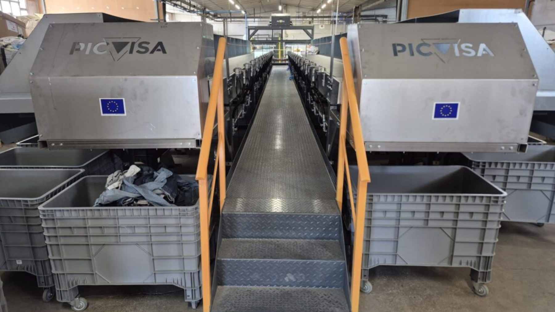 A person using a smartphone app to deposit used clothing into a modern, brightly colored TexMat smart recycling bin on a European city street.
