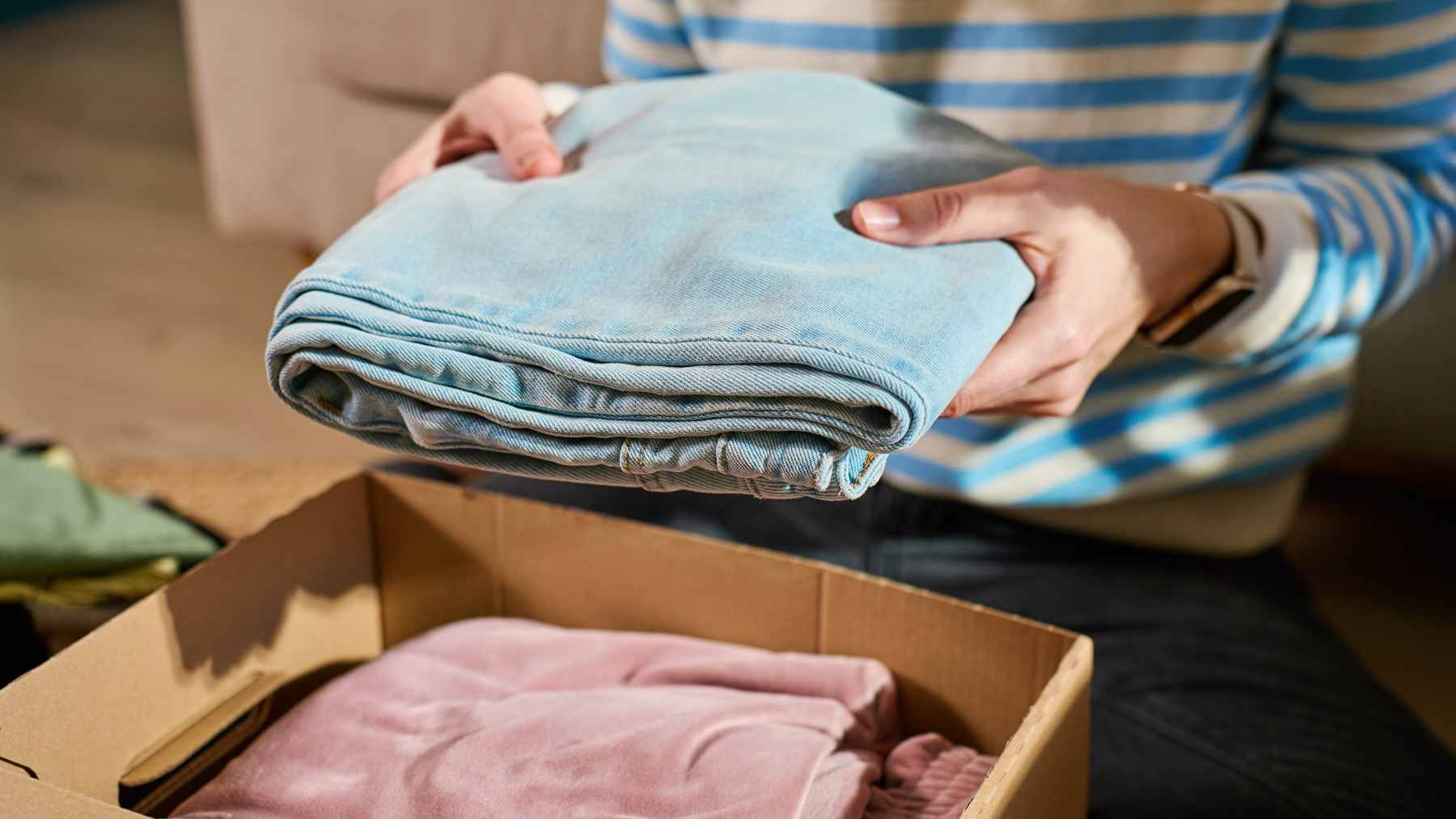 A person using a smartphone app to deposit used clothing into a modern, brightly colored TexMat smart recycling bin on a European city street.