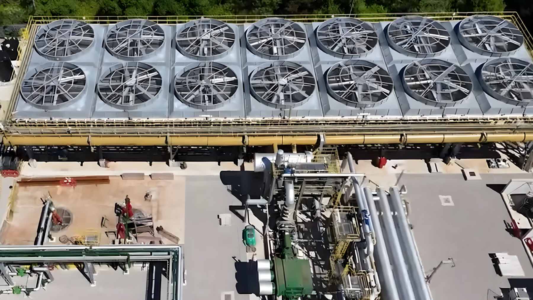 A wide view of the United Downs deep geothermal energy facility in Cornwall, featuring metal pipelines and vapor cooling systems against an overcast sky.