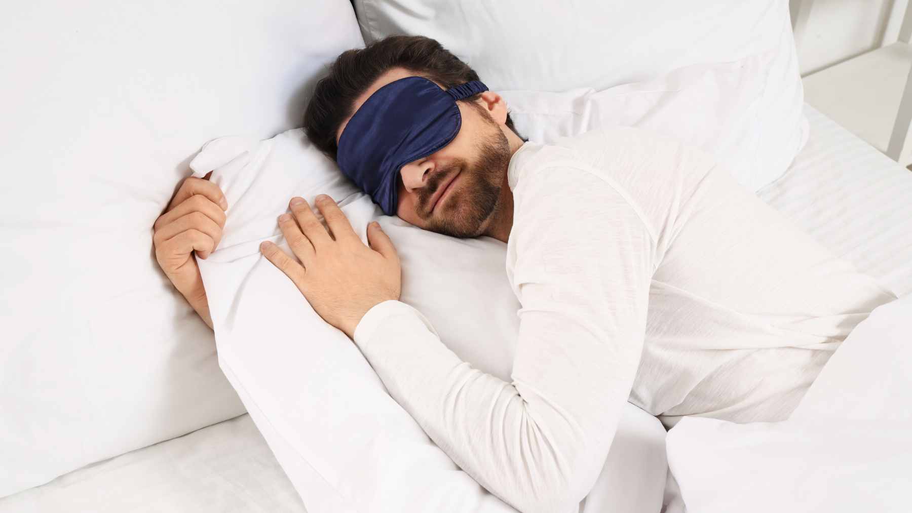 A person waking up in bed as bright morning sunlight streams through the bedroom window.