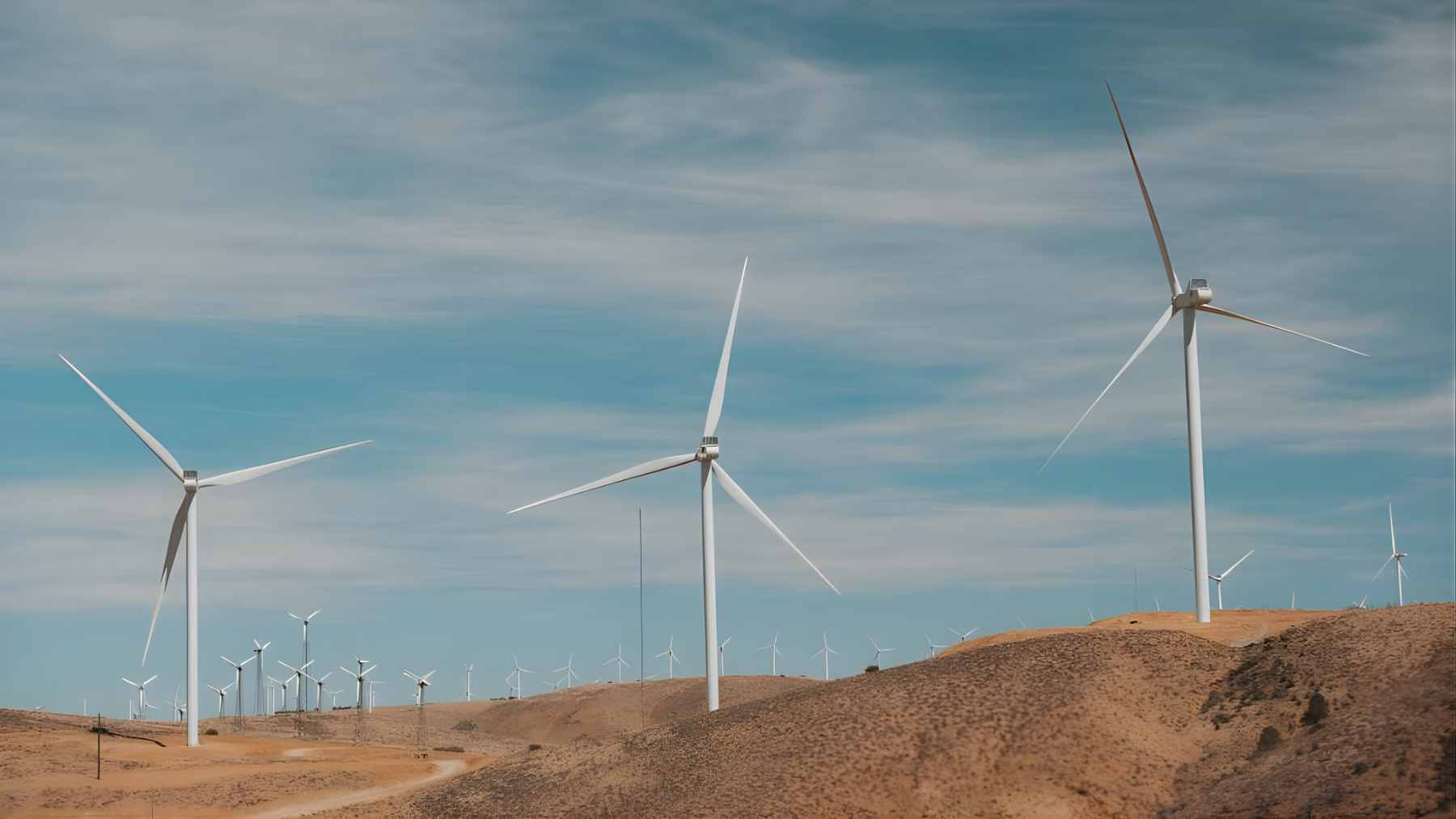 A sprawling wind farm stretching across the open landscape of Wyoming's Laramie Range under a cloudy sky.