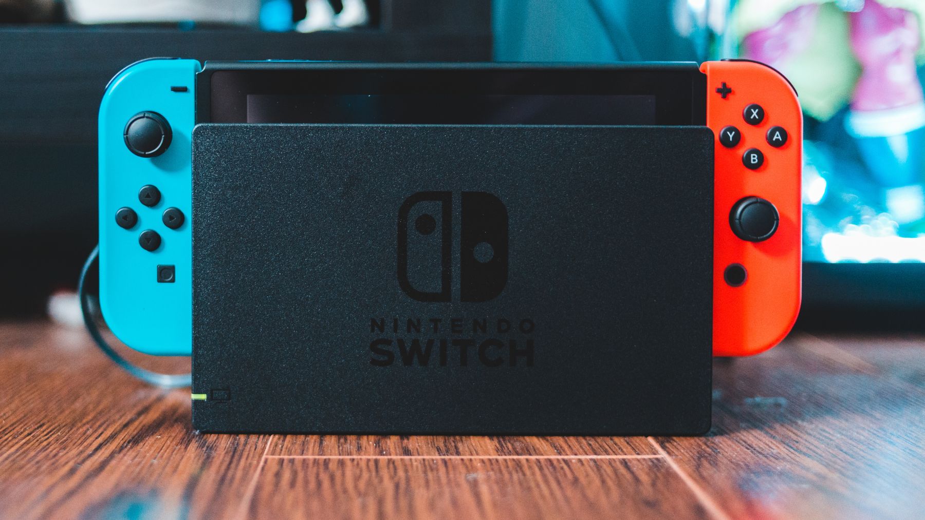 Consola Nintendo Switch en su base de carga junto a Joy-Cons azul y rojo, representando el nuevo modo de rendimiento 22.0.0..